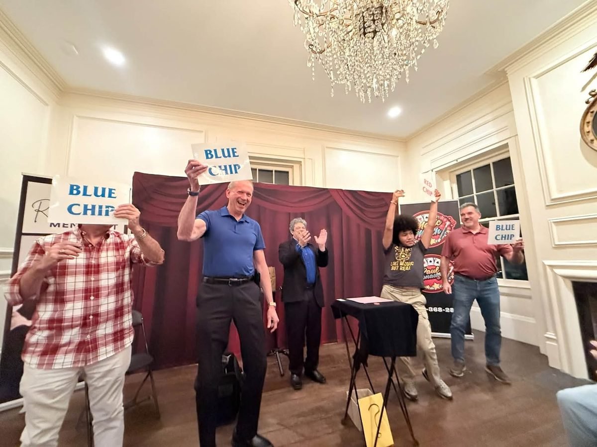 Guests on stage cheering and holding up Blue Chip signs during a Rick Silver show in Roswell