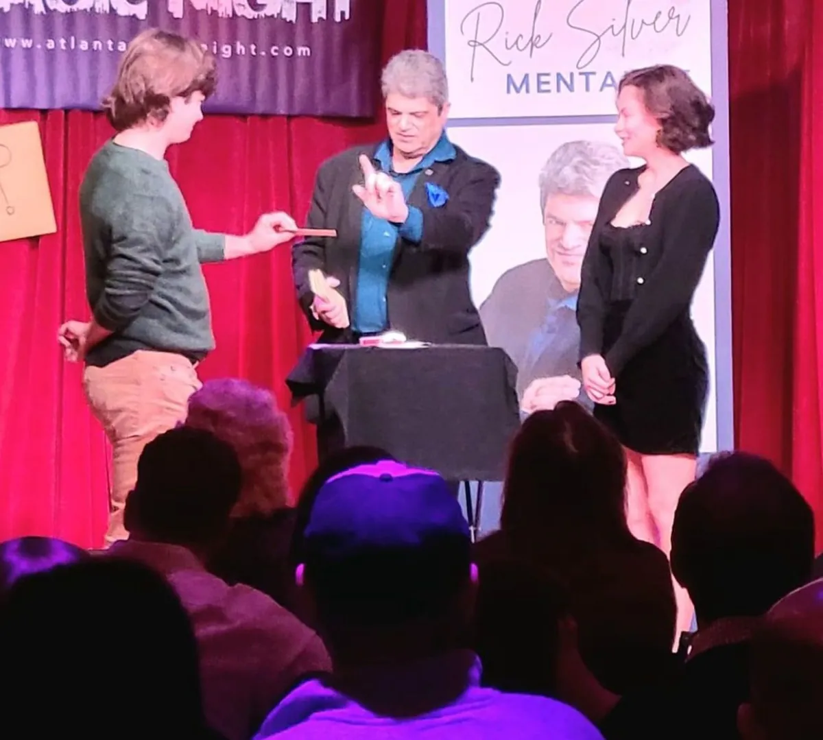 Mentalist Rick Silver on stage with two audience volunteers during a live show